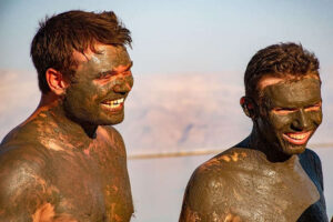 tourists covered in mud at the dead sea