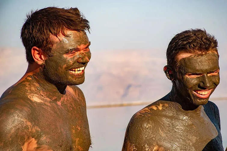 tourists covered in mud at the dead sea