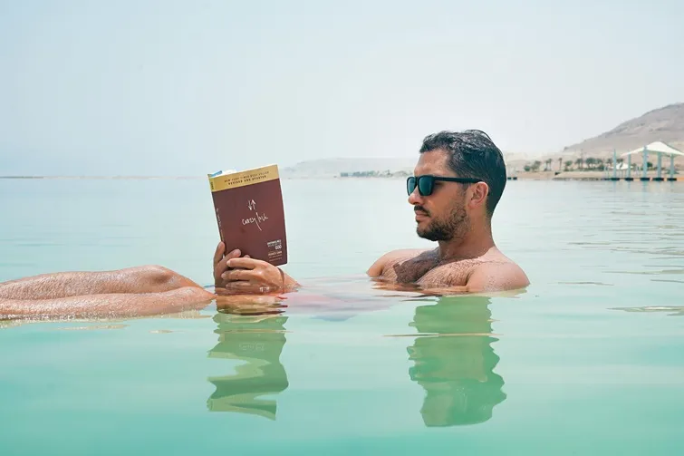 a man floating in the dead sea and reading a book